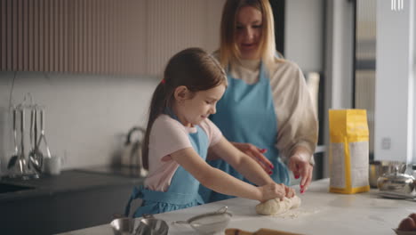 housewife-and-little-daughter-are-making-dough-for-bread-in-home-together-mother-is-kneading-pastry